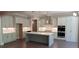Bright, open kitchen featuring modern appliances, white cabinets, island with white countertop and dark wood floors at 4525 Aiden Way, Cumming, GA 30041