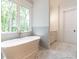 Luxurious bathroom with a freestanding tub, marble floors, a double vanity, and a large window at 410 Iroquois Ct, Covington, GA 30014