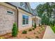 Close-up of the exterior, showing brickwork, black trim windows, landscaping, and a charming pathway at 410 Iroquois Ct, Covington, GA 30014