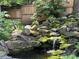 Picturesque moss-covered rock waterfall, pond, and lush landscaping is surrounded by a wooden fence at 1833 N Rock Springs Ne Rd, Atlanta, GA 30324