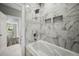Spa tub with marble tile surround and shower head, recessed nooks, and light gray walls at 4140 Camaron Way, Snellville, GA 30039