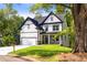 Two-story home boasts white siding, black trim, a two car garage, and a well-manicured lawn in a lush neighborhood at 4140 Camaron Way, Snellville, GA 30039