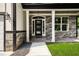 Inviting covered front porch with stone accents, white columns, and a modern front door with glass panels at 4140 Camaron Way, Snellville, GA 30039