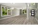 Open-concept living room with large windows, wood-look flooring, and modern lighting fixtures near the entry at 4140 Camaron Way, Snellville, GA 30039