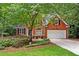 Charming brick home featuring a two-car garage and well-maintained landscaping, surrounded by lush trees at 1765 Redbud Way, Cumming, GA 30041