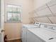 Functional laundry room featuring a washer, dryer, storage shelves, and a window at 1765 Redbud Way, Cumming, GA 30041