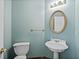 Charming half bathroom featuring a pedestal sink, decorative mirror, and toilet at 1765 Redbud Way, Cumming, GA 30041