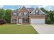 Charming two-story brick home featuring a well-manicured lawn, attached two car garage and inviting front entrance at 2359 Saint Kennedy Ln, Buford, GA 30518