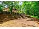 Brick home with screened porch and wood stairs that lead to a large lot and green foliage at 3030 Spalding Dr, Sandy Springs, GA 30350