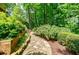 Backyard stone path winds through lush greenery and landscaping, creating a serene and inviting outdoor space at 3030 Spalding Dr, Sandy Springs, GA 30350