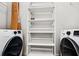 Bright laundry room features full-size washer and dryer plus shelving unit at 3324 Peachtree Ne Rd # 2718, Atlanta, GA 30326