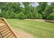 Expansive backyard features lush green grass and mature trees from stairs at 5515 Cheatam Ave, Cumming, GA 30040