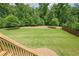 Large backyard features lush green grass and mature trees with stairs at 5515 Cheatam Ave, Cumming, GA 30040
