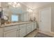 Bathroom featuring double vanities with granite counters, a large mirror, and white cabinets at 5515 Cheatam Ave, Cumming, GA 30040