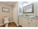 Bathroom with white vanity, granite countertop, framed mirror, and wood flooring at 5515 Cheatam Ave, Cumming, GA 30040