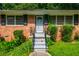 Detailed view of home exterior featuring a wrought iron security door, brick facade, and neatly trimmed landscaping at 379 Utoy Sw Cir, Atlanta, GA 30331