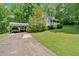 View of home and carport with long drive and green lawn surrounded by large trees at 144 Wiley Dr, Douglasville, GA 30134