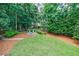 Tranquil backyard featuring mature trees, lush landscaping, and a charming fire pit area with seating at 4115 Falls Ridge Dr, Johns Creek, GA 30022
