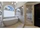 Bathroom featuring a white tub, tiled floors, an arched window, and a glass shower with a bench at 4115 Falls Ridge Dr, Johns Creek, GA 30022