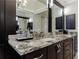 Bathroom featuring marble countertop, dark cabinets, framed mirrors, and modern fixtures at 4115 Falls Ridge Dr, Johns Creek, GA 30022