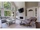 Living room with a painted brick fireplace, large arched window, and built-in shelving at 4115 Falls Ridge Dr, Johns Creek, GA 30022