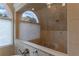 Shower featuring natural tile, arched window, two shower heads, and a built in granite bench at 4115 Falls Ridge Dr, Johns Creek, GA 30022