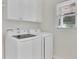 Well-lit laundry room featuring a side-by-side washer and dryer, white cabinets, and a window bringing in natural light at 4206 Moccasin Trl, Woodstock, GA 30189