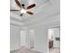 Bright bedroom featuring tray ceilings, a ceiling fan, and doorways leading to an en suite bathroom and closet at 4206 Moccasin Trl, Woodstock, GA 30189