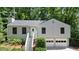 Charming home with manicured lawn, inviting entryway stairs, and two-car garage nestled among mature trees at 7025 Stone Wood Nw Dr, Kennesaw, GA 30152