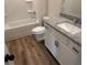 Bright bathroom with granite vanity, white cabinets, wood look floors, and tub with shower at 118 Longhorn Way, Auburn, GA 30011
