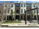 A modern three-story townhouse with white and brown accents, set against a backdrop of lush greenery at 358 Olmstead Way # 25, Alpharetta, GA 30022