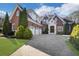 Stunning brick home featuring a three-car garage, mature landscaping, and a beautiful stone entryway at 821 Camden Park Ct, Atlanta, GA 30342