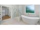 Bright bathroom features a soaking tub, a glass shower, marble counters and floors and a walk-in closet at 103 Maddox Rd, Buford, GA 30518