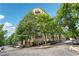 Exterior view of a mid-rise condo building lined with trees and street parking at 711 Cosmopolitan Ne Dr # 802, Atlanta, GA 30324