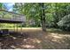 A view of the expansive backyard featuring a deck, mature trees, and an air conditioning unit at 120 E Cainwood E Ct, Atlanta, GA 30349