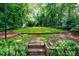 A lush backyard with a moss lawn and stone steps, surrounded by mature trees and landscaping at 2811 Alpine Ne Rd, Atlanta, GA 30305