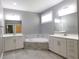 Bright primary bathroom featuring dual sinks, a soaking tub, and neutral tiling at 330 La Perla Dr, Sugar Hill, GA 30518