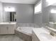 Bright primary bathroom featuring dual sinks, a soaking tub, and neutral tiling at 330 La Perla Dr, Sugar Hill, GA 30518