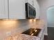 Kitchen features a smooth cooktop, granite countertops, a tile backsplash, and white cabinetry at 330 La Perla Dr, Sugar Hill, GA 30518