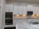This bright kitchen has stainless steel double oven, granite countertops, and white cabinetry at 330 La Perla Dr, Sugar Hill, GA 30518