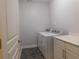 Laundry room with washer, dryer, tile floor, and door at 330 La Perla Dr, Sugar Hill, GA 30518
