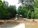 Community playground features slides, towers, and climbing equipment in a wooded and landscaped area at 330 La Perla Dr, Sugar Hill, GA 30518