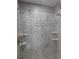 Modern shower featuring elegant tilework, rainfall showerhead, and convenient built-in shelving at 330 La Perla Dr, Sugar Hill, GA 30518