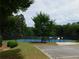 Community tennis courts with a blue playing surface, bench seating, and surrounded by trees at 330 La Perla Dr, Sugar Hill, GA 30518