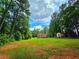 Large backyard with lush green grass and mature trees, showcasing the exterior of the inviting home at 4086 Rex Road, Rex, GA 30273