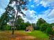 Scenic view of a two-story home with a well-manicured lawn and parking surrounded by towering trees under a cloudy sky at 4086 Rex Road, Rex, GA 30273