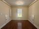 Bright bedroom featuring hardwood floors, trim, modern lighting fixture and a window with views of the front yard at 1417 Wind Chime Ct, Lawrenceville, GA 30045