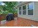 A wooden back deck features a grill and three large windows, inviting outdoor relaxation and entertainment at 202 Roseman Way, Woodstock, GA 30188