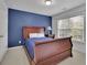 Bedroom featuring a large wooden bed frame, blue accent wall, and window with blinds for ample natural light at 202 Roseman Way, Woodstock, GA 30188