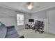 A bedroom featuring a gray sofa, a ceiling fan, a desk with gaming equipment, and wainscoting detail at 202 Roseman Way, Woodstock, GA 30188